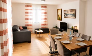 Modernes Wohn- und Esszimmer mit grauem Sofa, Holzesstisch und Fernseher